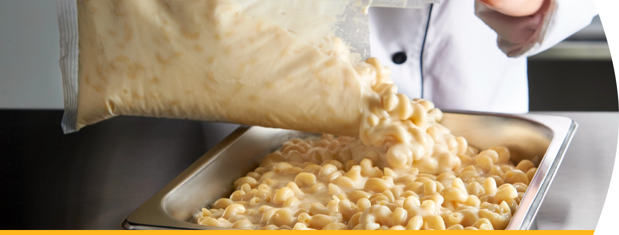 White Cheddar Macaroni and Cheese being poured into stainless steel pan