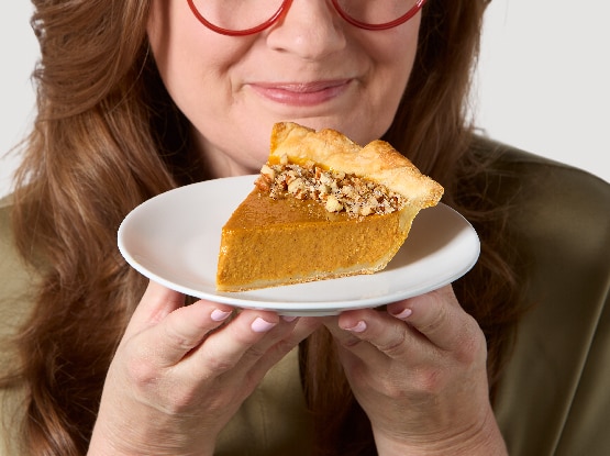 woman with red glasses holding a slice of Libby's pumpkin pie on white plate
