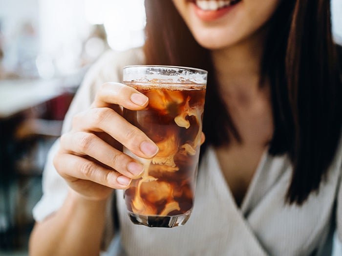 woman holding a glass with iced coffee