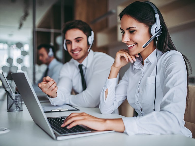 man and woman with headsets working on laptops