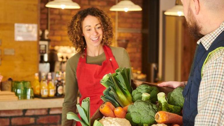 Farmer delivering a basket of local produce to a foodservice cafe owner