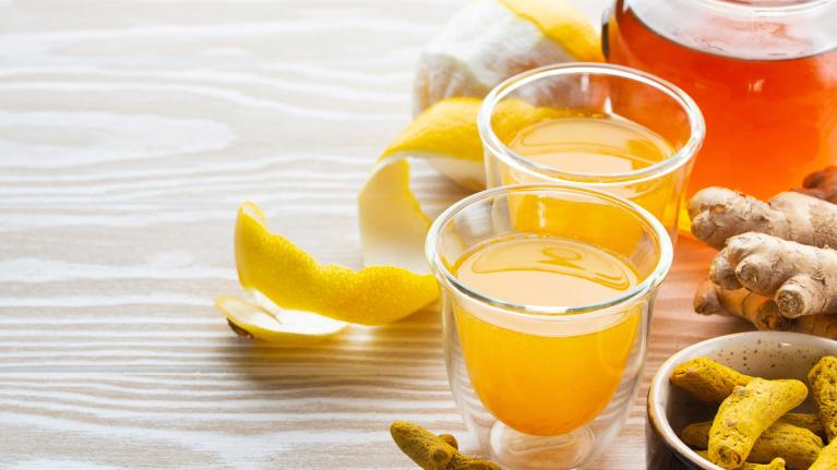 Lemon peel and glasses of juice on table