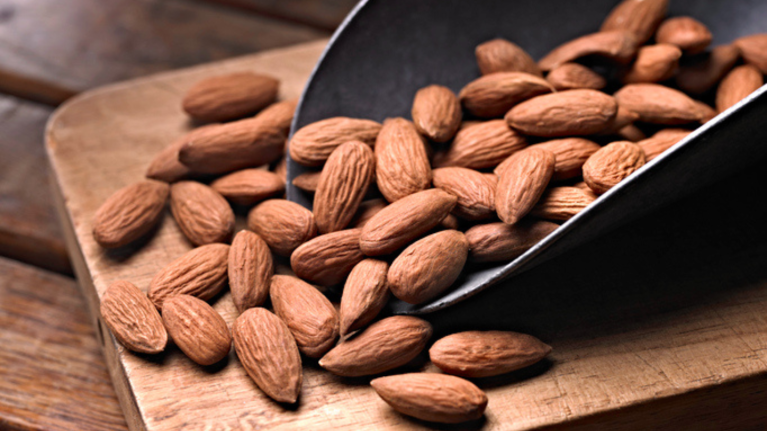 Scoop of nuts on wooden board