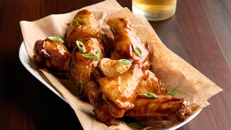 glazed chicken wings in basket on table