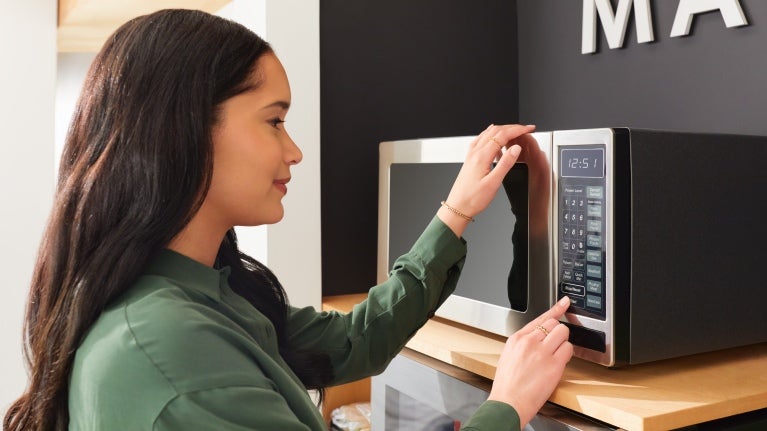 woman pressing buttons on microwave