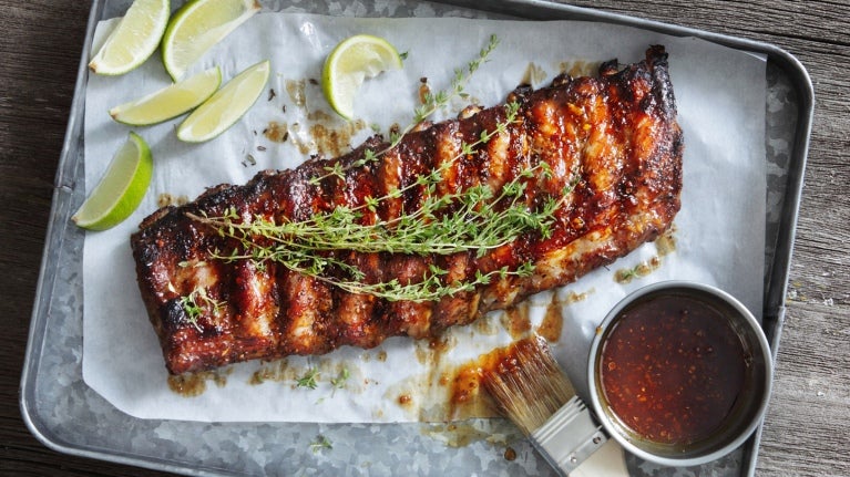 slab of barbecue ribs on parchment paper on metal tray