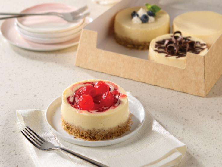 carnation milk strawberry topped cheesecake on a white plate with other cheesecake in background