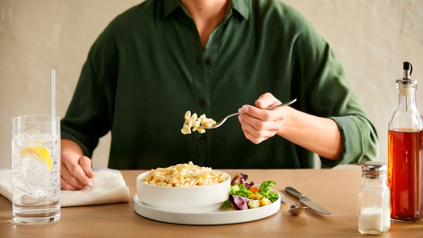 man at a table holding a fork with pasta on it